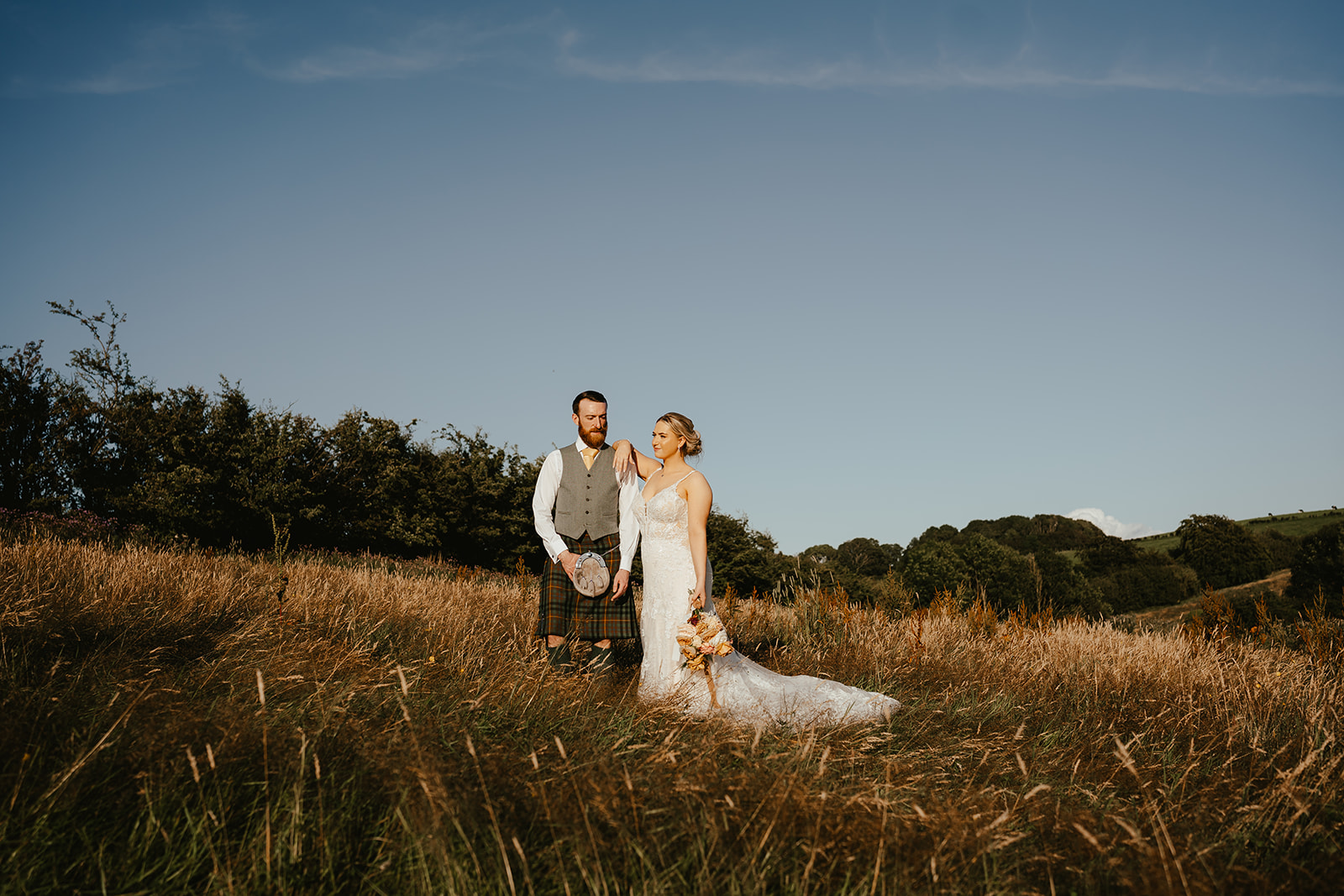 Sarah + Jamie Bride and groom standing in field during golden hour