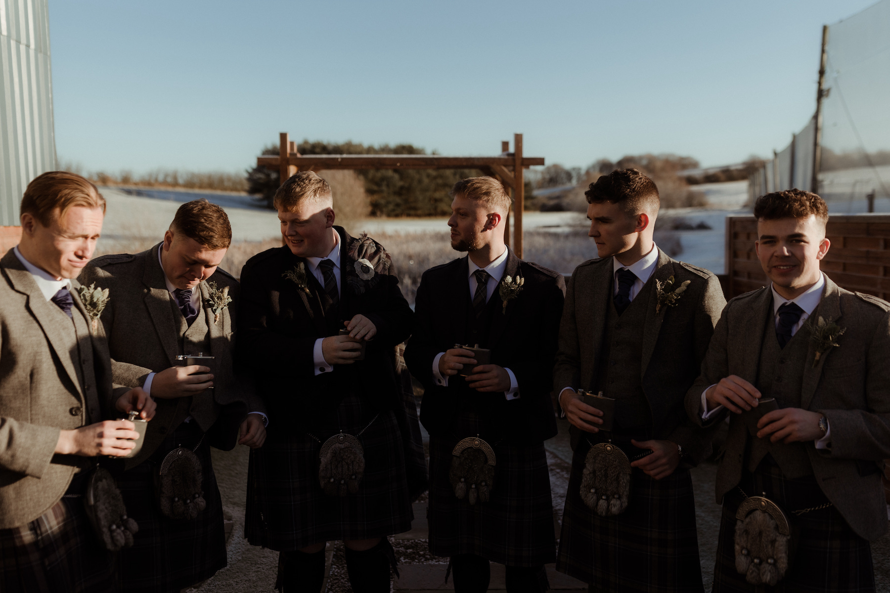 roomsmen in kilts sharing a moment outside on a frosty winter morning at Roodlea Barn.