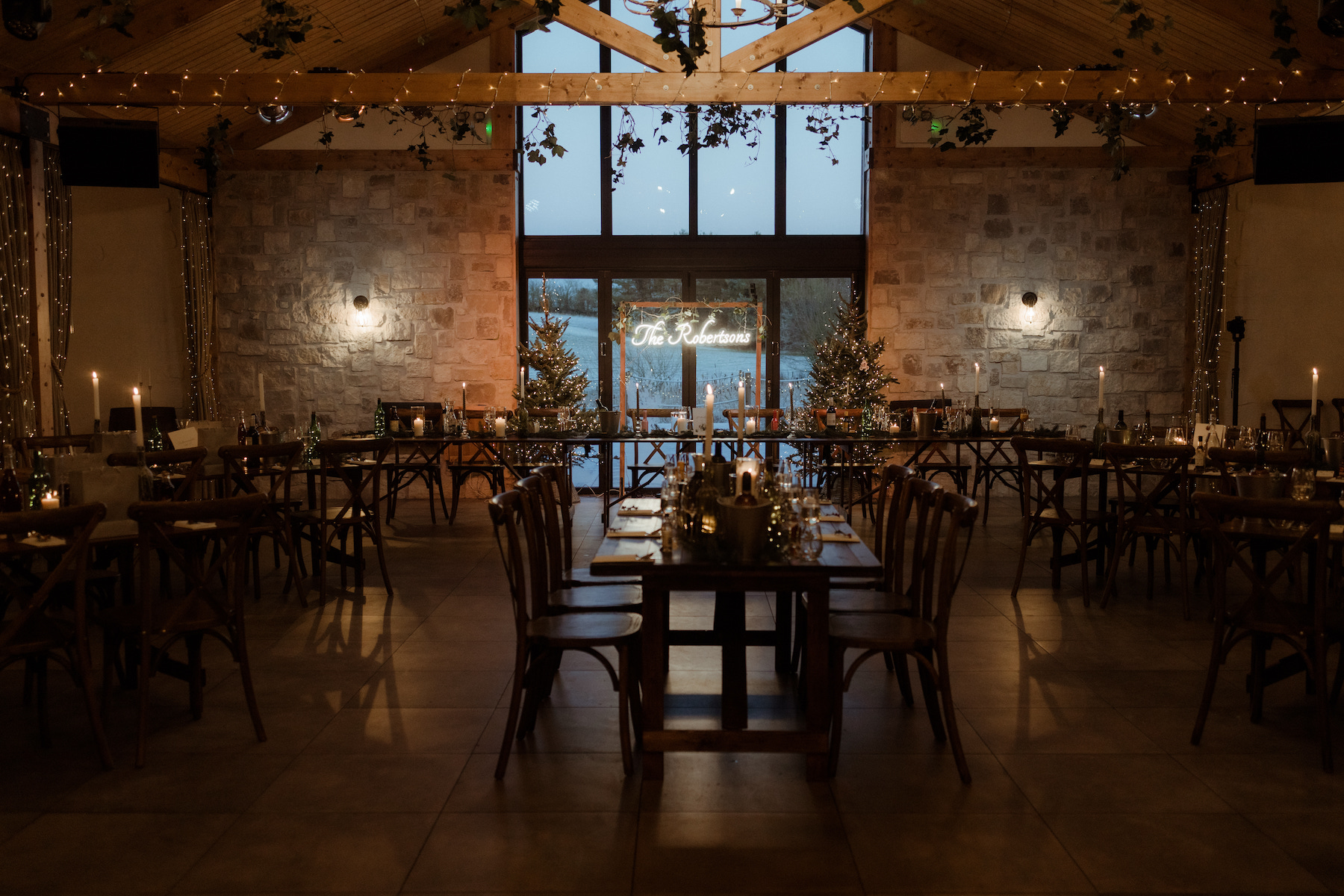 Winter wedding reception at Roodlea Barn with Christmas trees and a personalised neon sign at the top table.